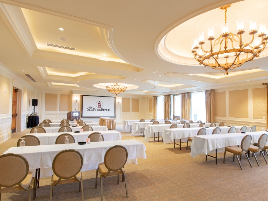 The Heritage Room at the Harbour Town Clubhouse setup in a theater style seating facing a large screen for a meeting. 