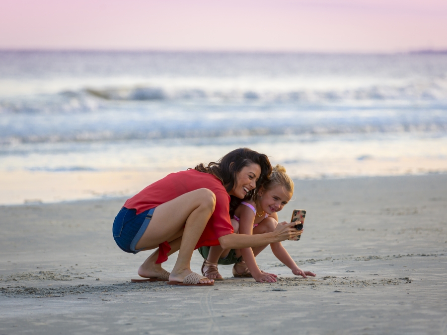 Mom and daughter taking a photo on the beach
