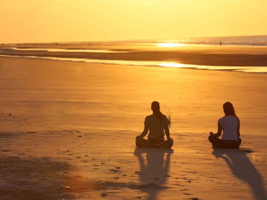 Two people doing yoga on the beach 