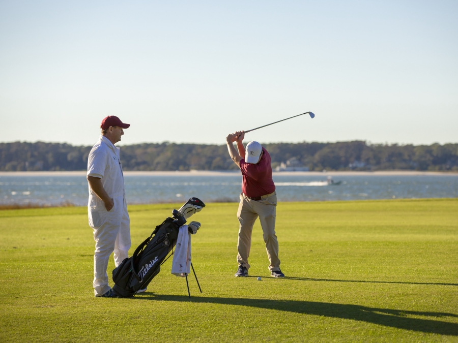 Two men golfing with the ocean in the background 