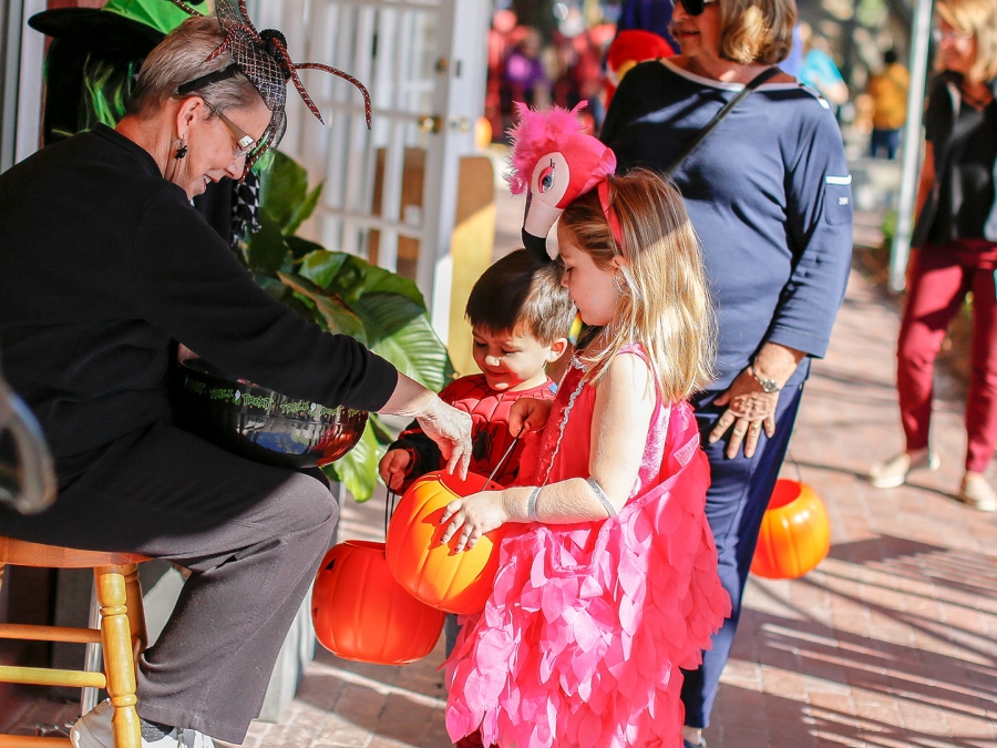 Children dressed in Halloween costumers receiving candy from Harbour Town Shops owner giving out candy at Halloween on the Harbour in Sea Pines.