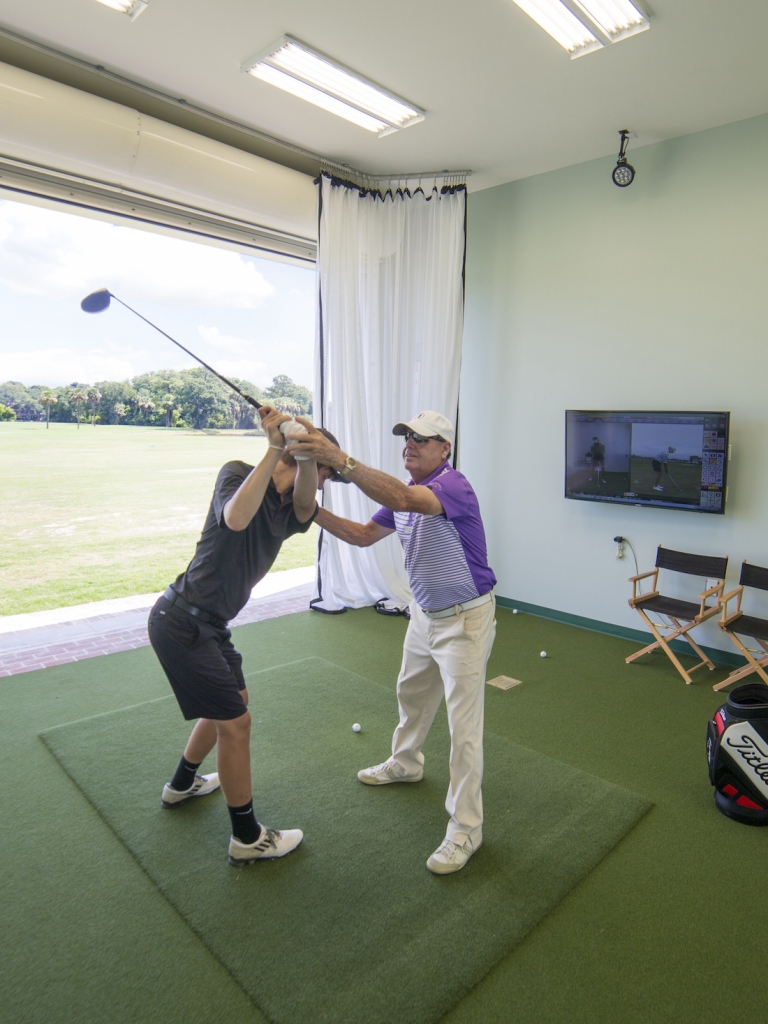 Golfer practicing his swing with the help of a coach 