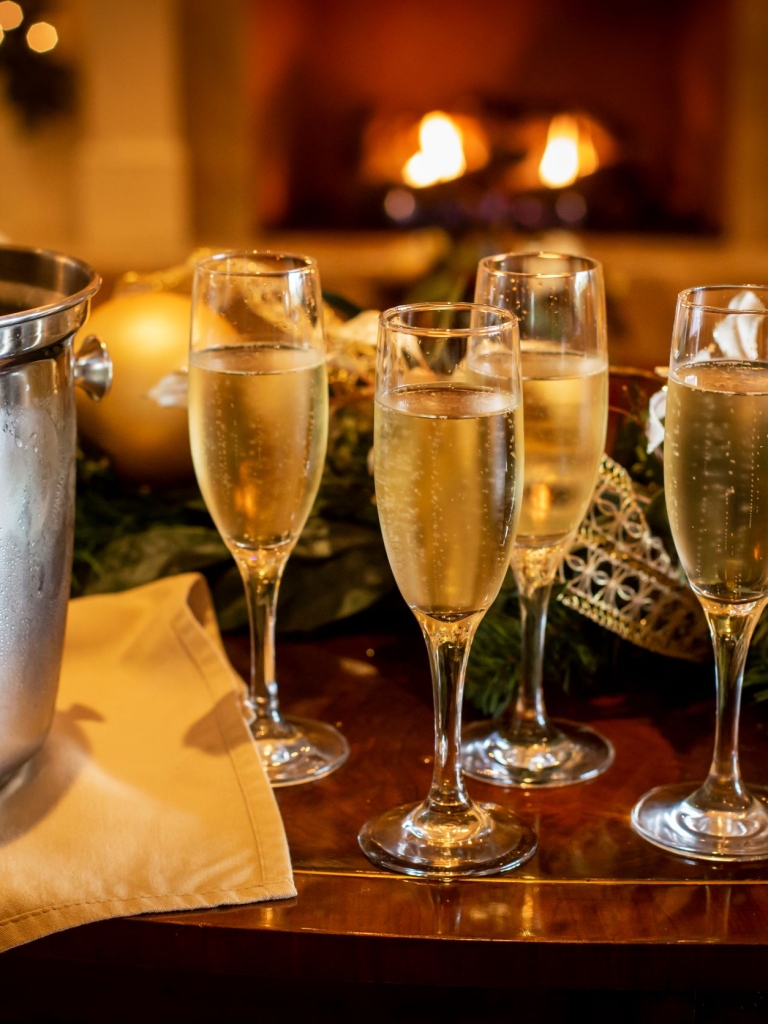 Four champaigns glasses and a champagne bottle resting in an ice bucket in front of a fireplace at Links, an American Grill.
