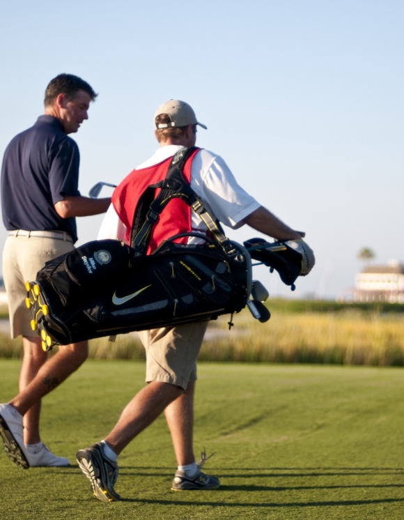 A man and caddie walking the golf course 
