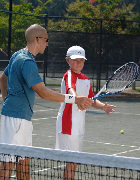 Boy being taught tennis by an instructor 
