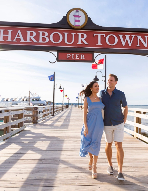 A couple walking along the harbour town pier 