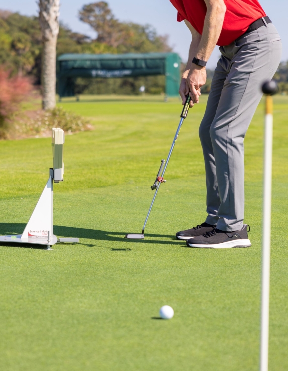 Golfer with putter hitting ball into the hole with the SAM Putt Lab technology. 