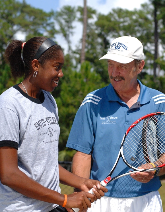 Instructor teaching a women tennis