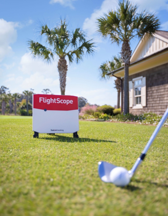 A golf club and ball on the grass in front of the FlightScope technology. 
