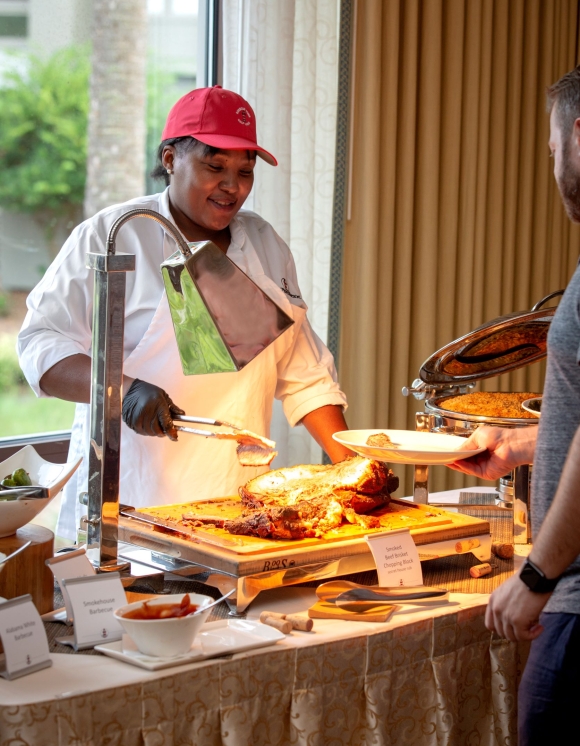 A member of the catering team serving barbecue to a guest. 