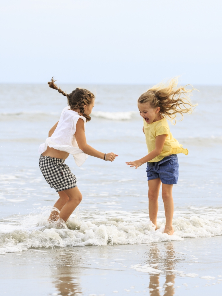 Two young girls playing in the ocean waves 