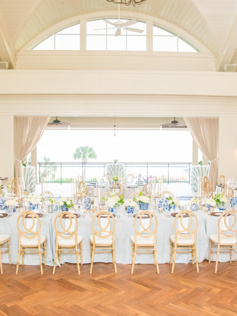 The Atlantic Room at the Sea Pines Beach Club setup for a wedding with a long table in front of the open accordion doors leading out to the Atlantic Deck overlooking the Atlantic Ocean.