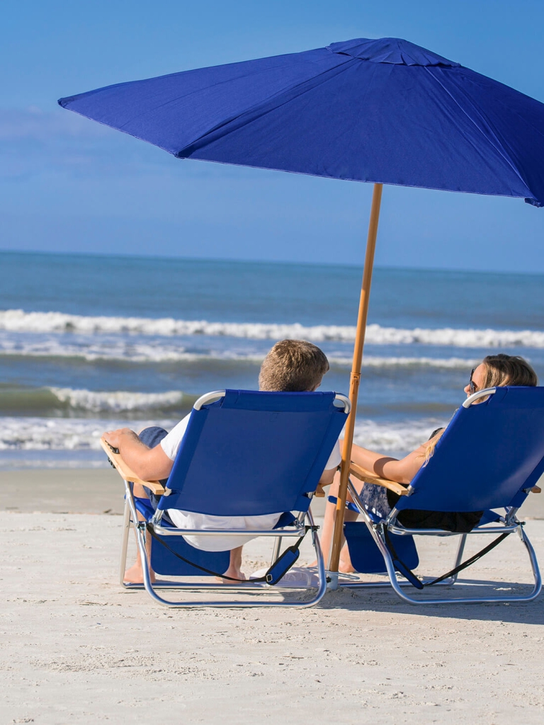 Couple on the beach with beach chairs and umbrella 