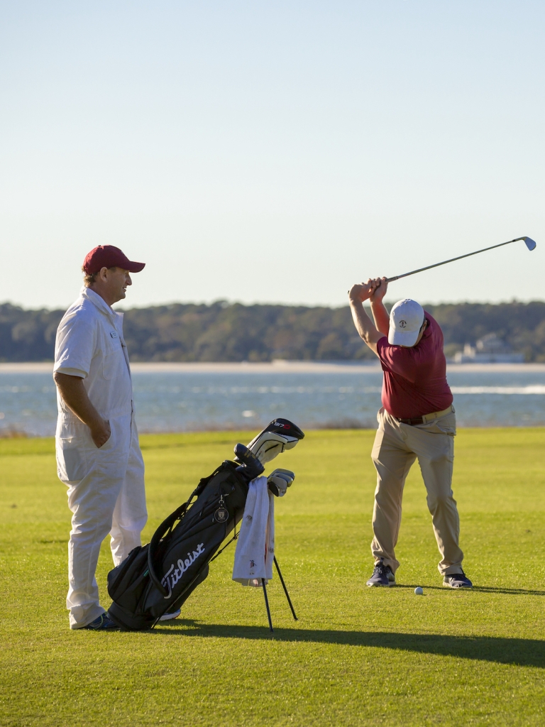 Two men golfing with the ocean in the background 