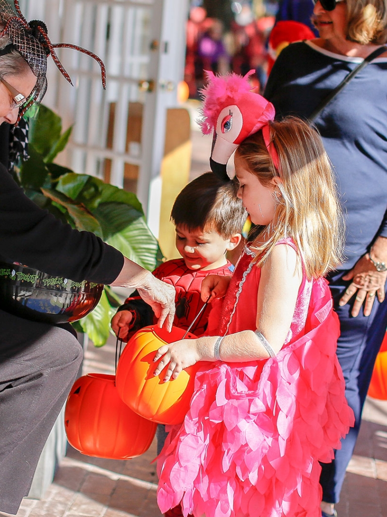 Children dressed in Halloween costumers receiving candy from Harbour Town Shops owner giving out candy at Halloween on the Harbour in Sea Pines.