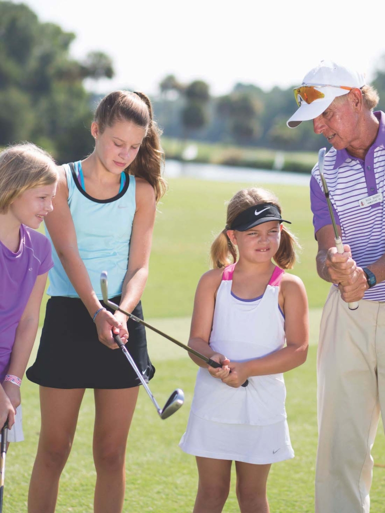 Golf coach teaching a group of children  