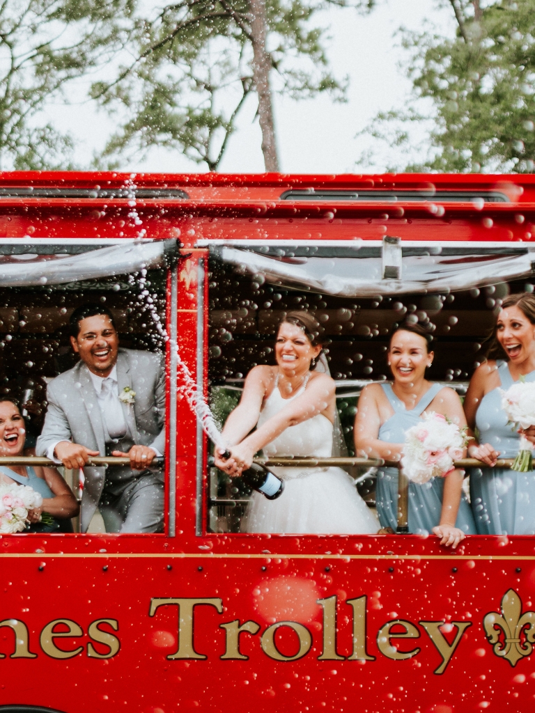 Wedding party popping champagne on a red trolley 