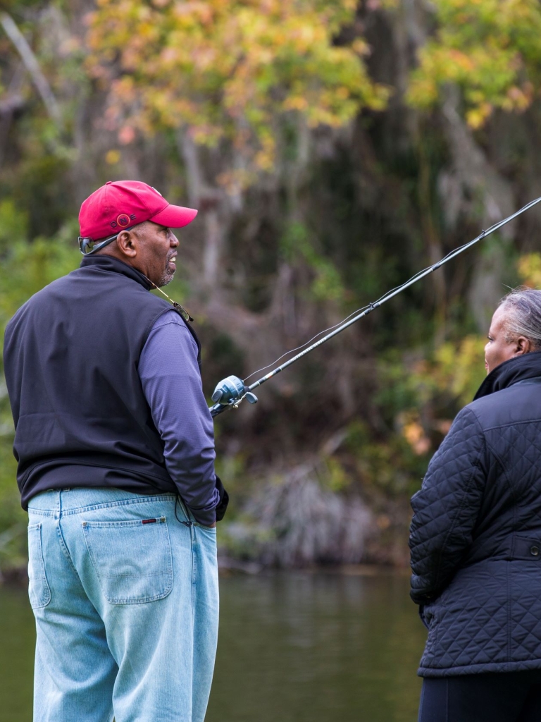 Couple standing by lake while the man is holding a fishing pole.