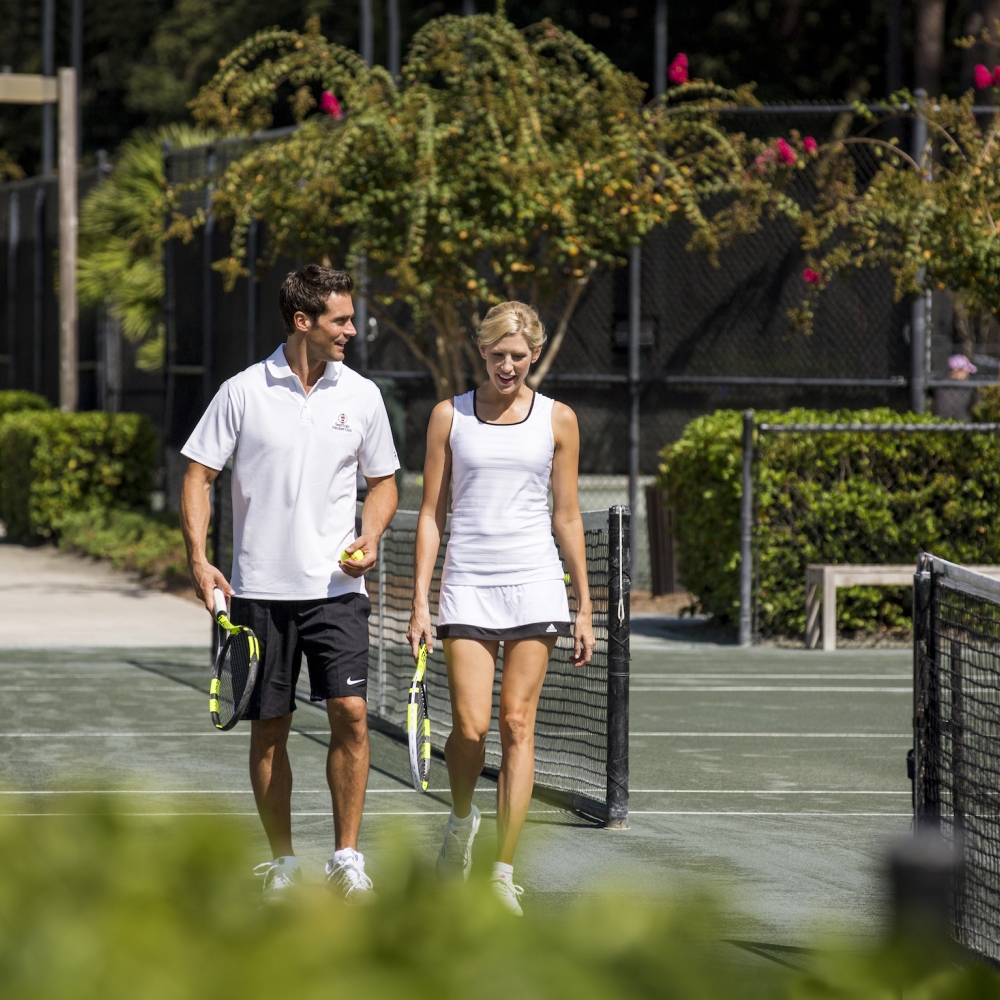 Man and women walking along the tennis court 