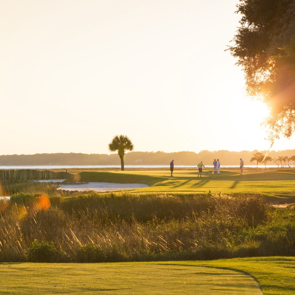 A group of golfers on the course at sunset 