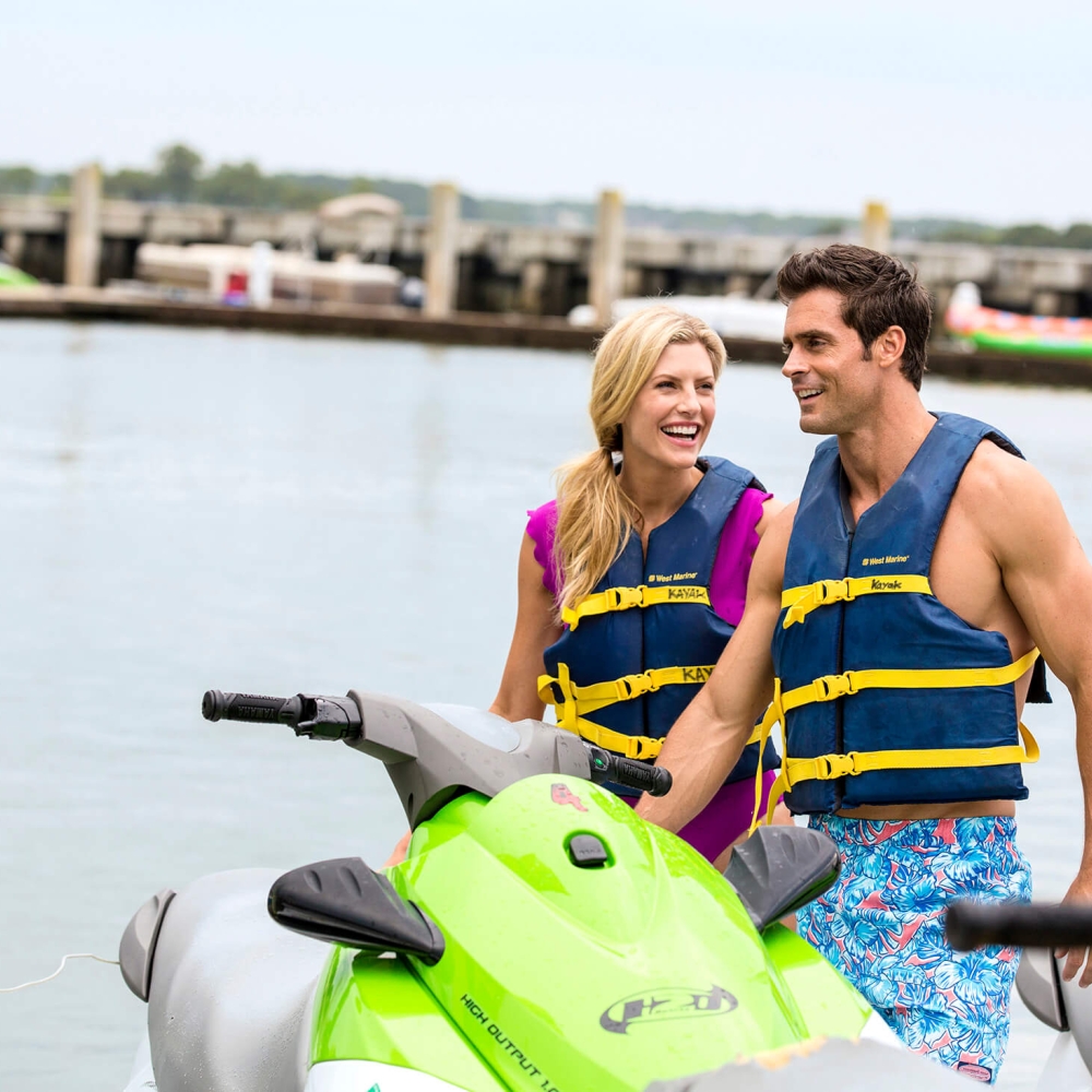 Couple laughing and standing next to a jet-ski 