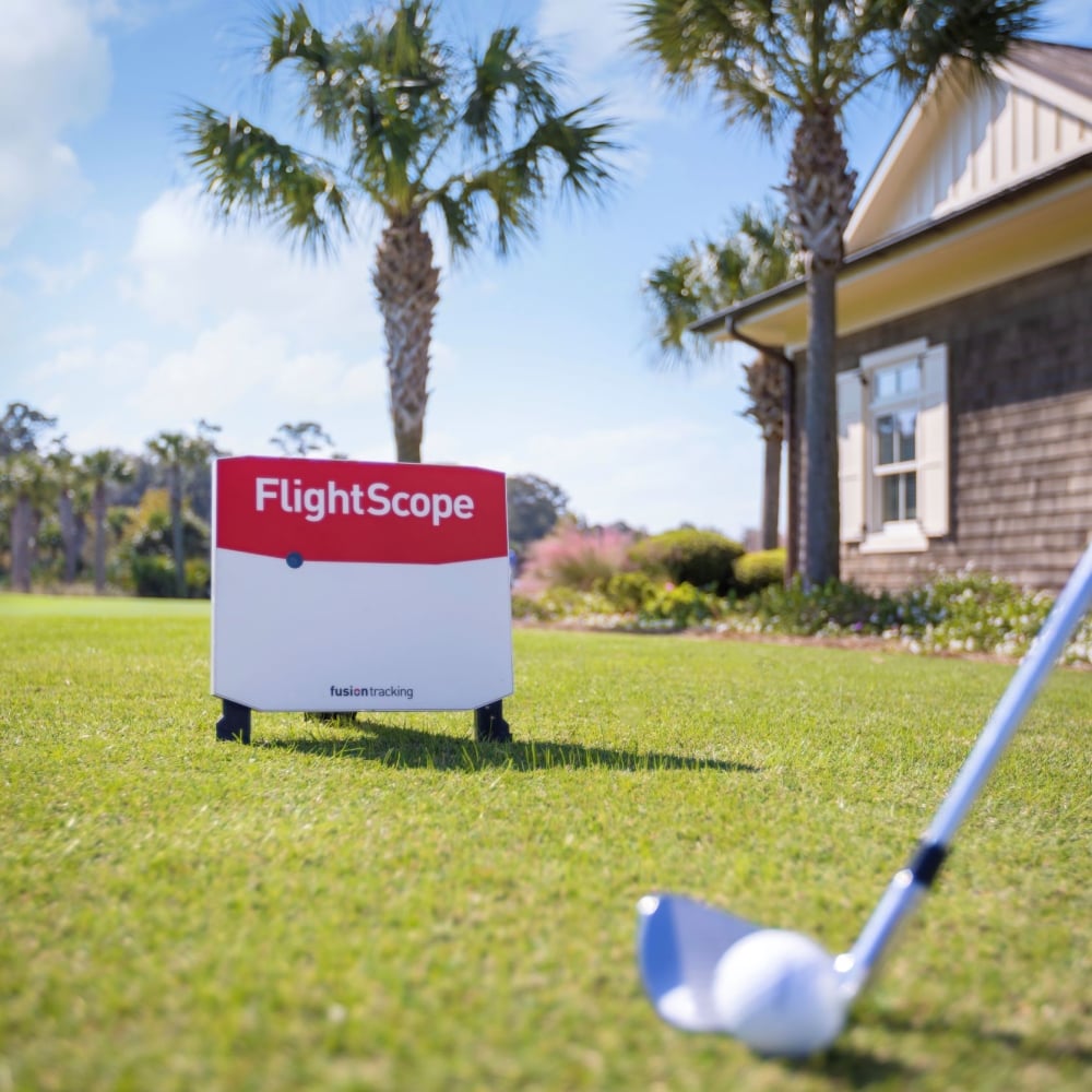 A golf club and ball on the grass in front of the FlightScope technology. 